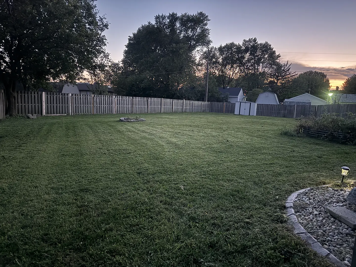 A mowed backyard with a wooden fence and trees at dusk, from the 2Guysandalawnmower portfolio.